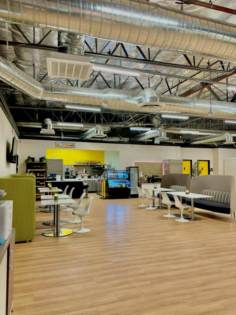 Large industrial-style communal dining area with exposed ductwork and cafe seating.