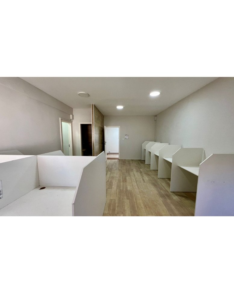 Coworking area with white privacy booths and light wood flooring.