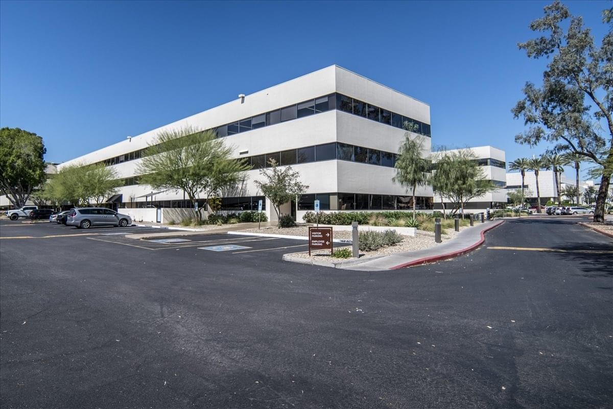 Exterior view of the white multi-story Camelback Square office building under a clear blue sky.