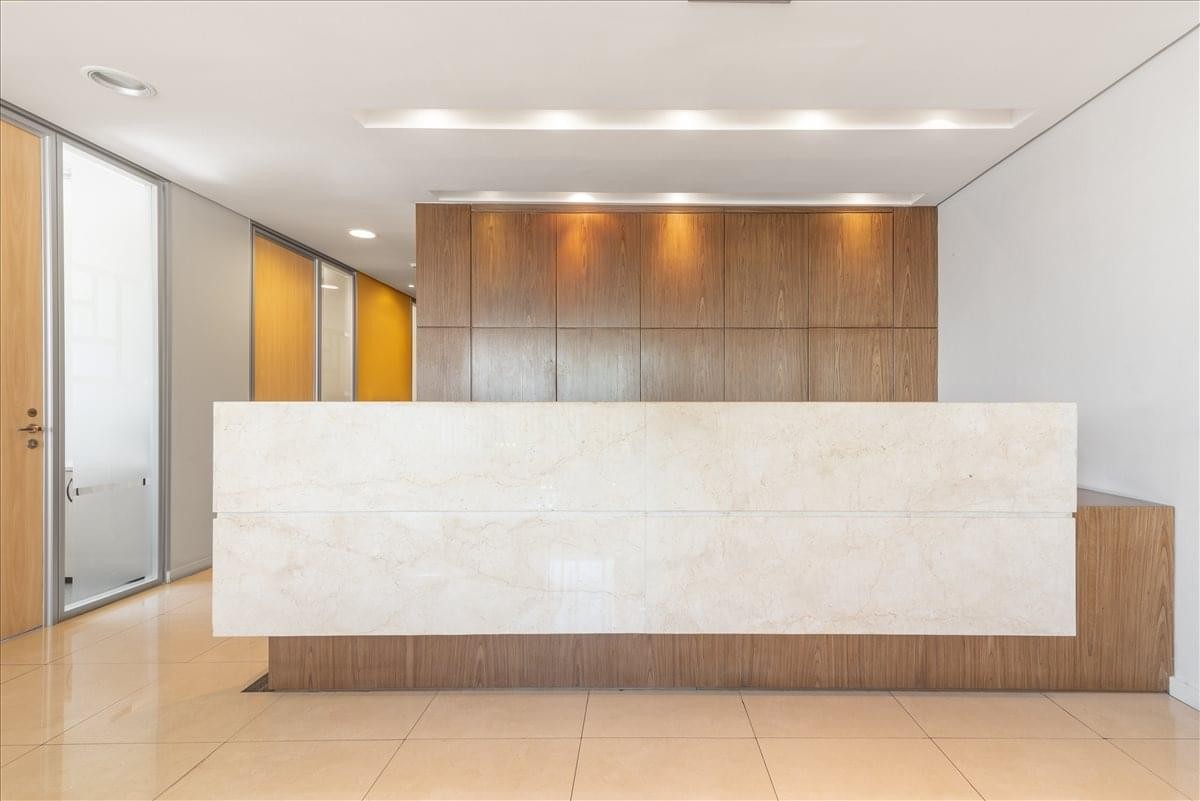 Bright reception area of the Cícero Dias Tower featuring a marble front desk and warm wood paneling.