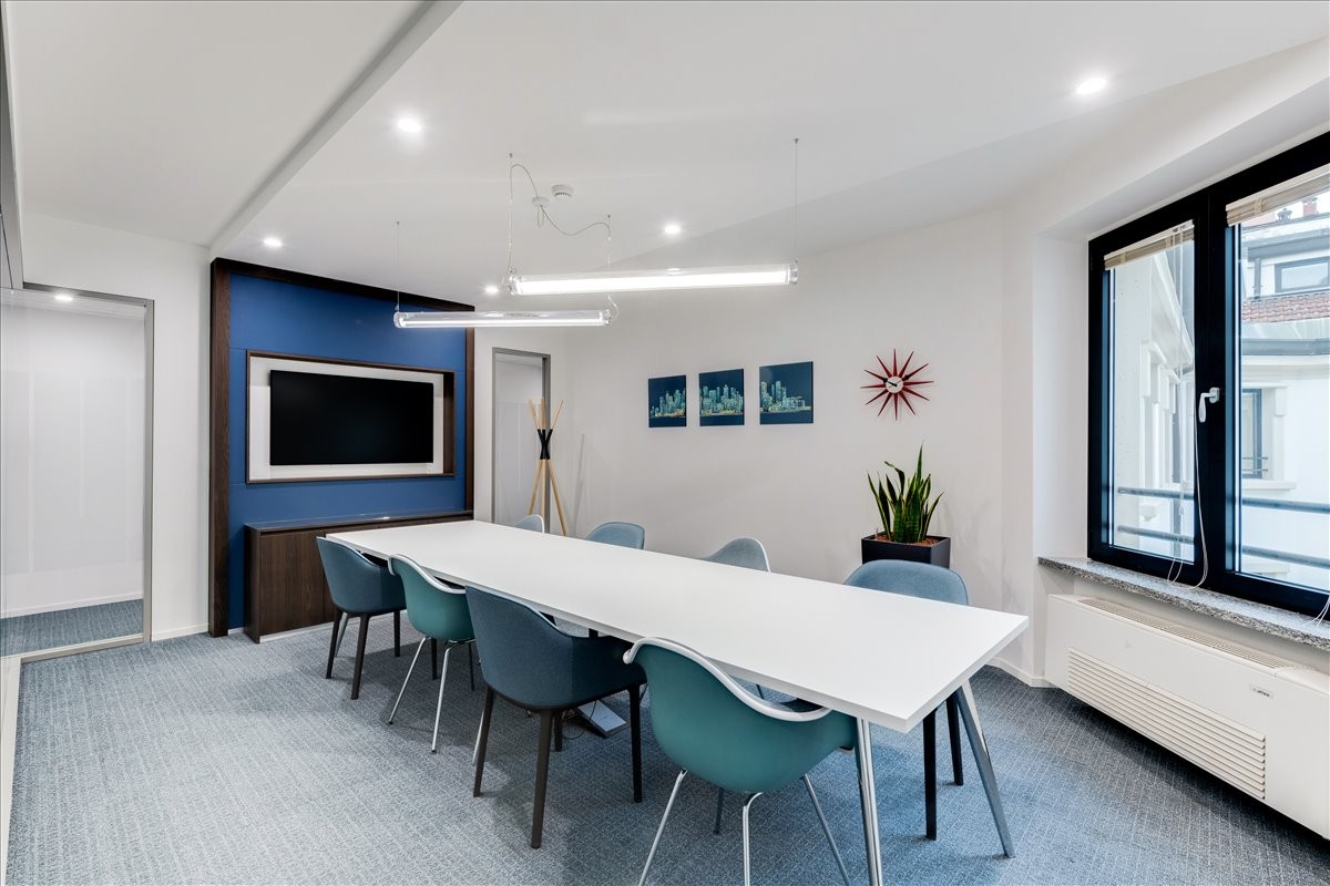 Modern conference room at 70 Melvin Robson Avenue, featuring a blue accent wall and teal chairs.