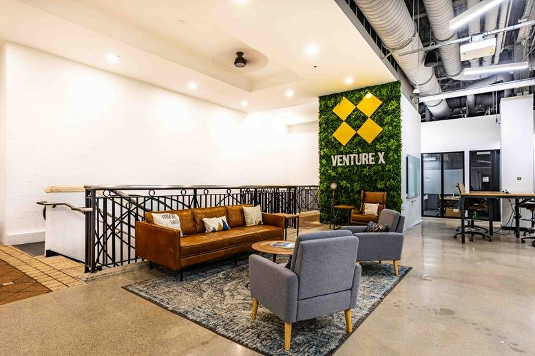 Spacious lounge at 700 S. Rosemary, 204 with a leather sofa, grey armchairs, and a green moss feature wall.