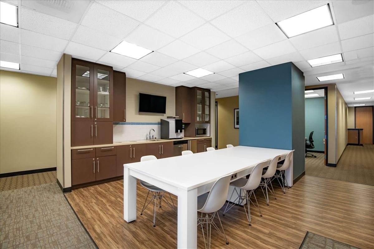 Modern breakroom at Pacific Center featuring a large white communal table and kitchen facilities.
