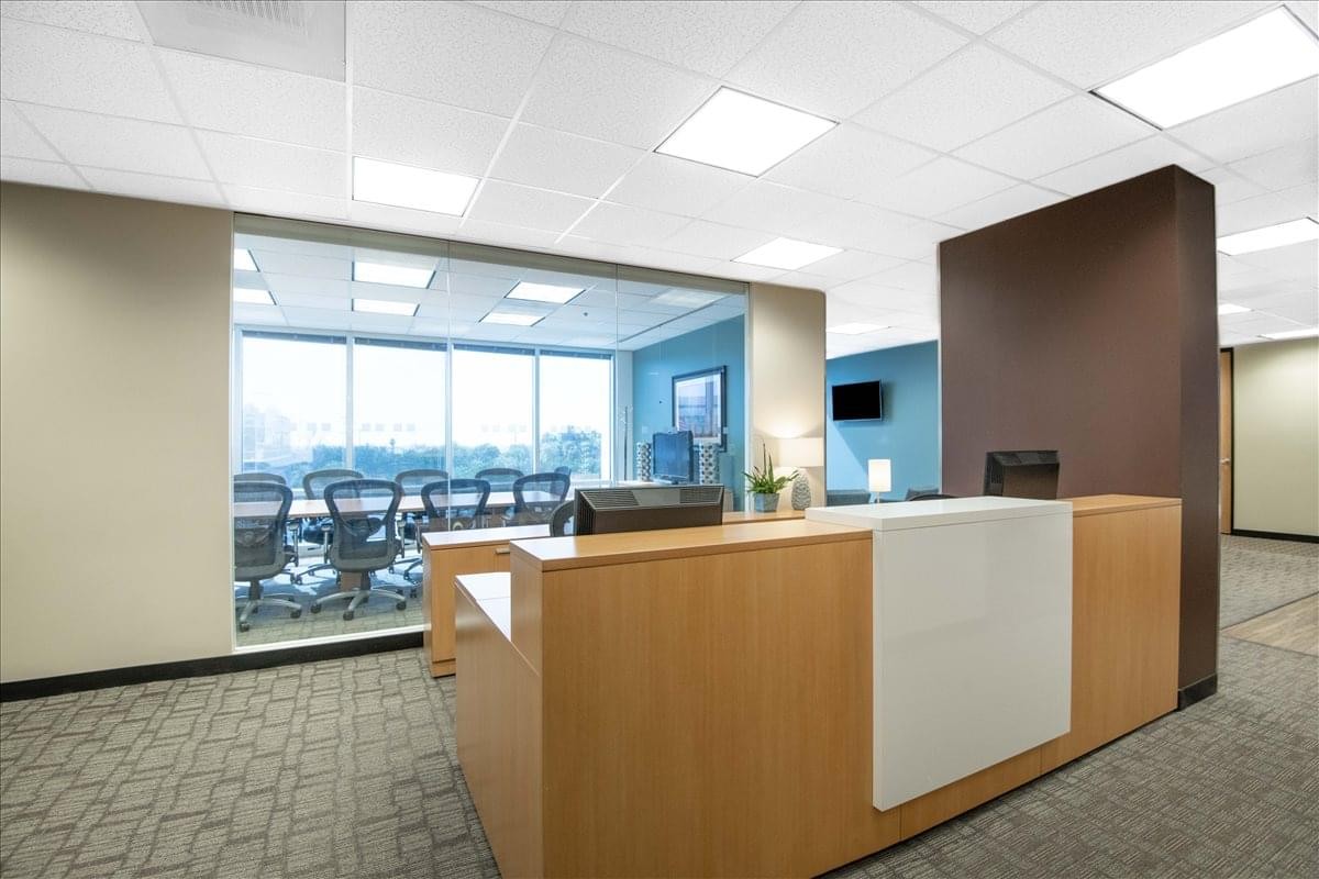 Bright reception area at Pacific Center featuring a wooden front desk and glass-walled conference room.