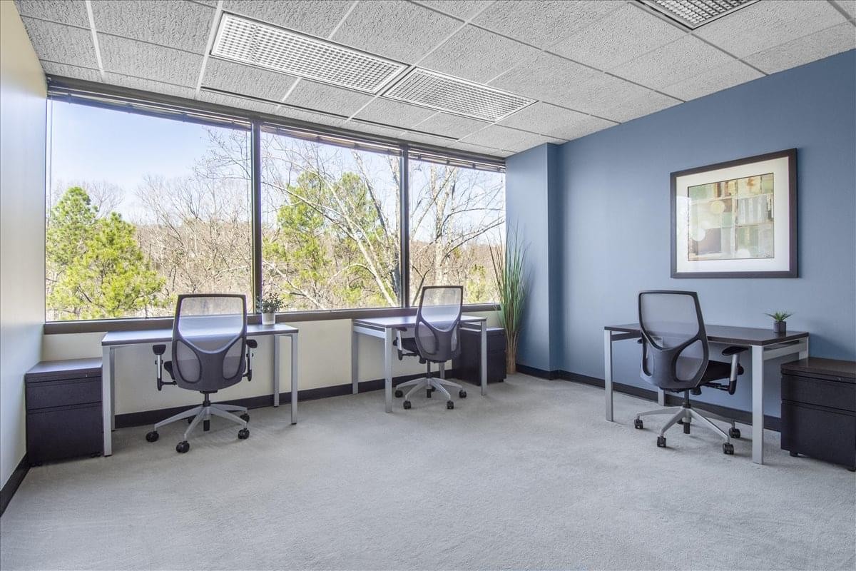 Spacious three-person workspace at 7027 Old Madison Pike, Suite 108 with blue accent walls and framed art.