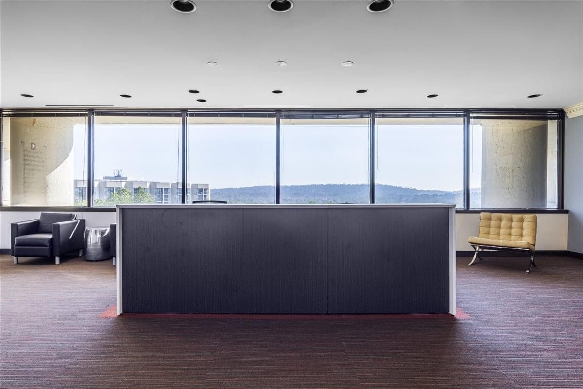 Wide-angle view of a modern reception desk in front of floor-to-ceiling windows.