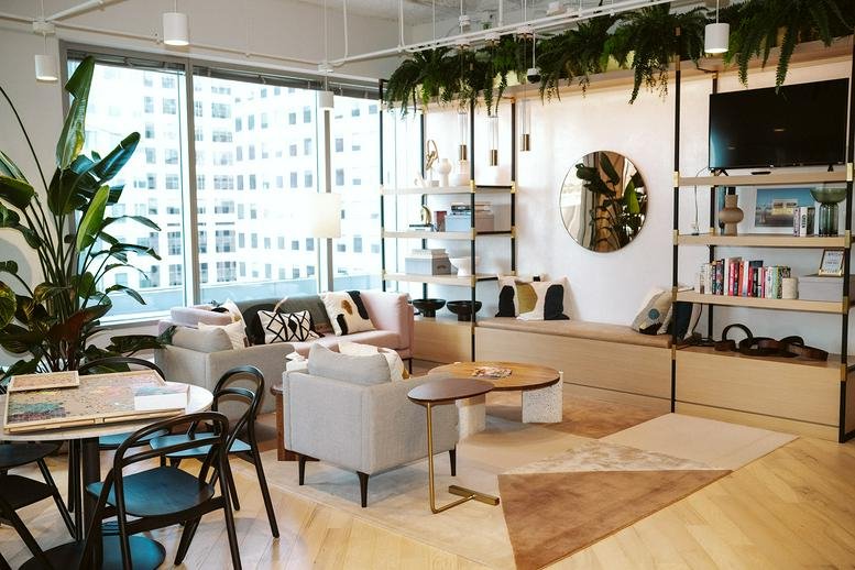 Bright communal lounge at 717 Texas Avenue featuring modern sofas, potted plants, and city views.