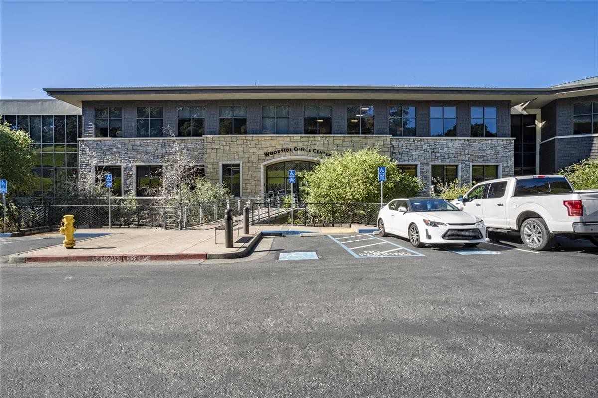 Exterior view of the stone and glass facade of Woodside Office Center at 7250 Redwood Drive.