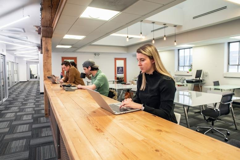 Spacious coworking area at 73 W. Monroe featuring a long wood-topped communal desk and natural light.