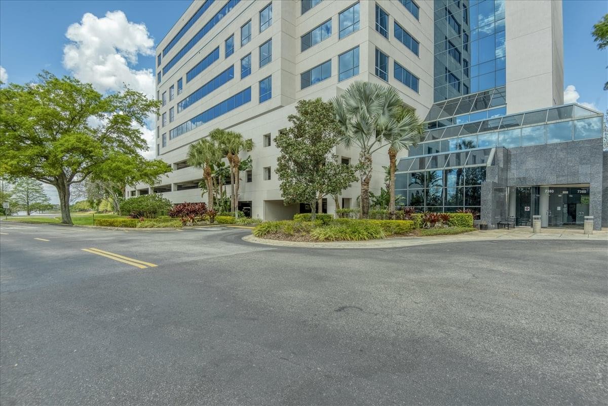 Exterior view of the multi-story Sand Lake Center building featuring glass accents and professional landscaping.