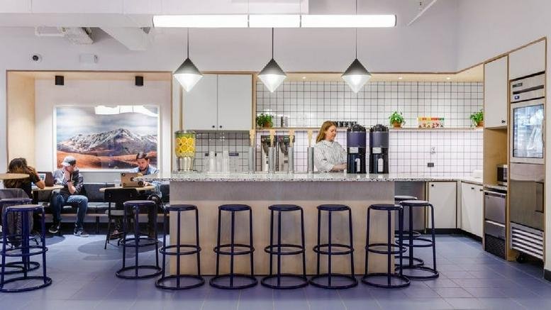 Spacious communal kitchen and cafe area at 750 Lexington Avenue with pendant lighting and blue stools.
