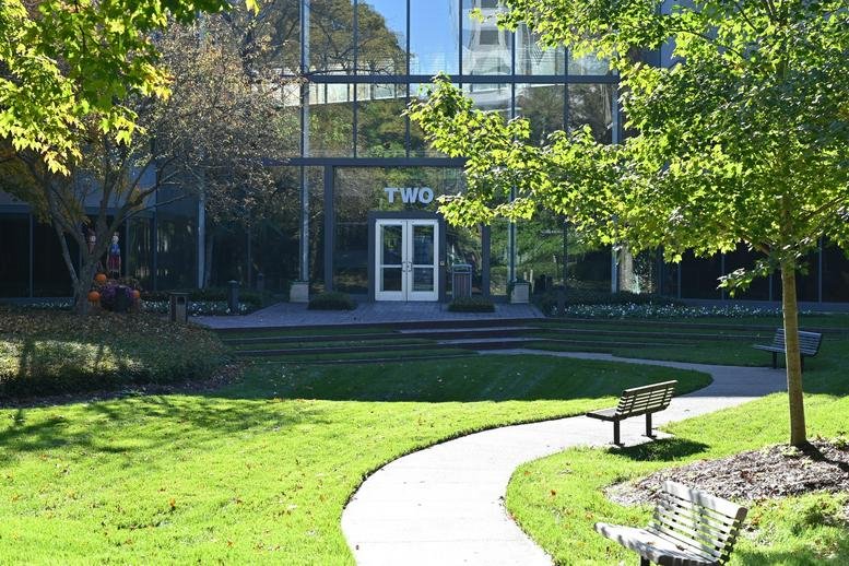 Exterior entrance of 2 Brentwood Commons with glass facade and surrounding greenery.