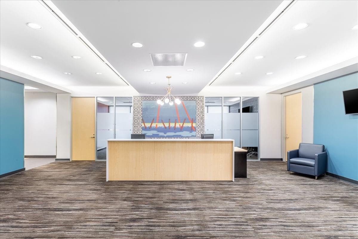 Spacious reception area at Lighton Tower with a large light-wood desk and blue accent walls.