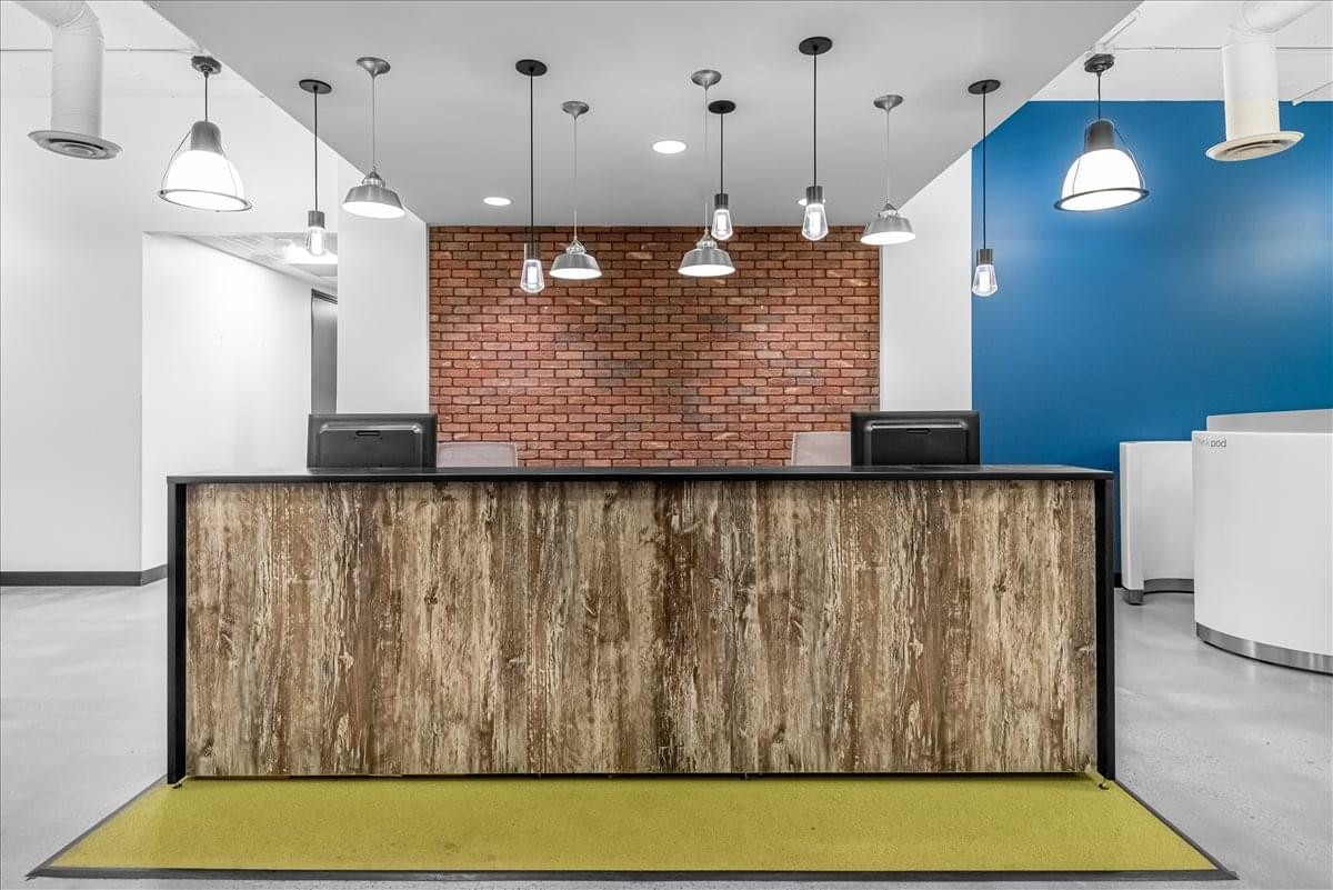 Professional reception desk at Tamarac Plaza II featuring a wood-textured front and brick accent wall.