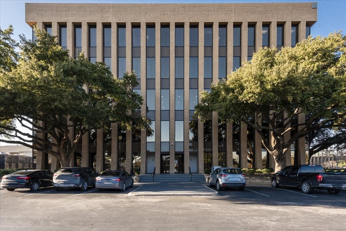 Exterior view of the stone facade at Chase Park Center with mature trees and parking.