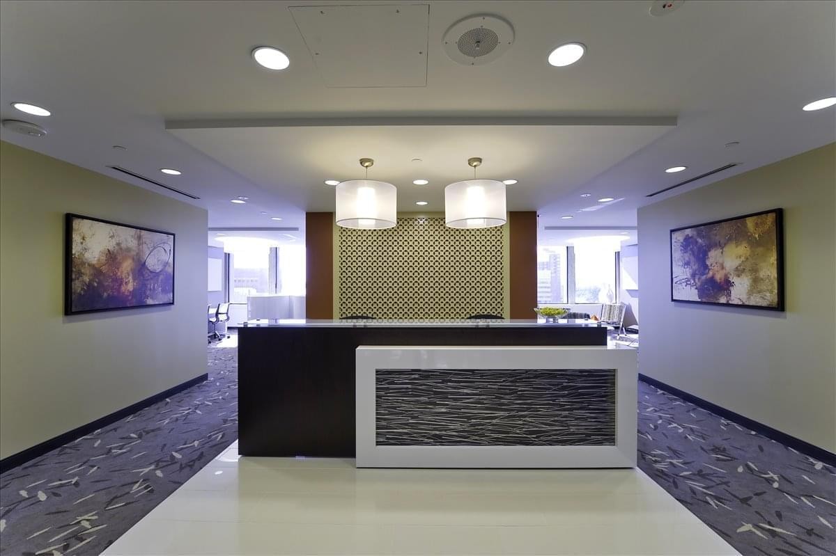 Reception area with a dark wood desk, white textured facade, and geometric feature wall.