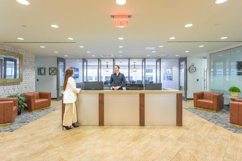 Professional reception area at 777 Brickell Avenue, 5th Floor with warm wood floors and modern desk.