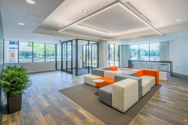 Reception lobby with modular grey and orange seating and bright LED lighting.
