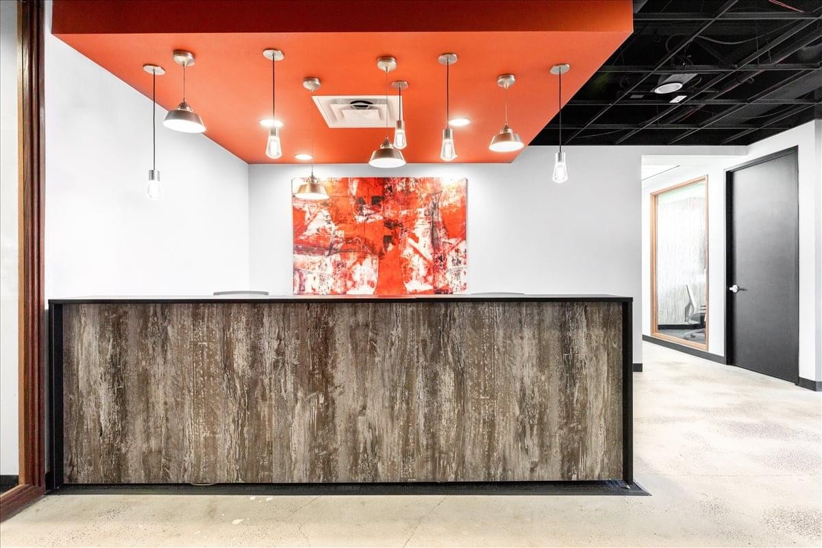 Reception area at the Sevens Building with a wood-panelled desk and orange ceiling.