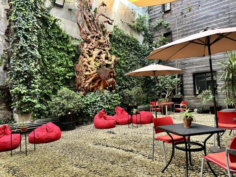 Lush outdoor courtyard with red bean bags and cafe seating at San Miguel Chapultepec.
