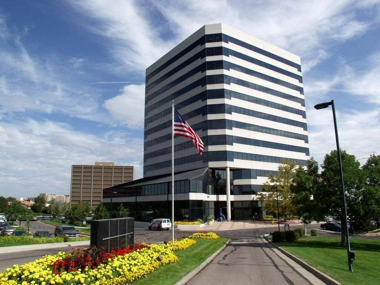 Exterior of the multi-story office building at 7887 East Belleview Avenue with manicured flower beds.