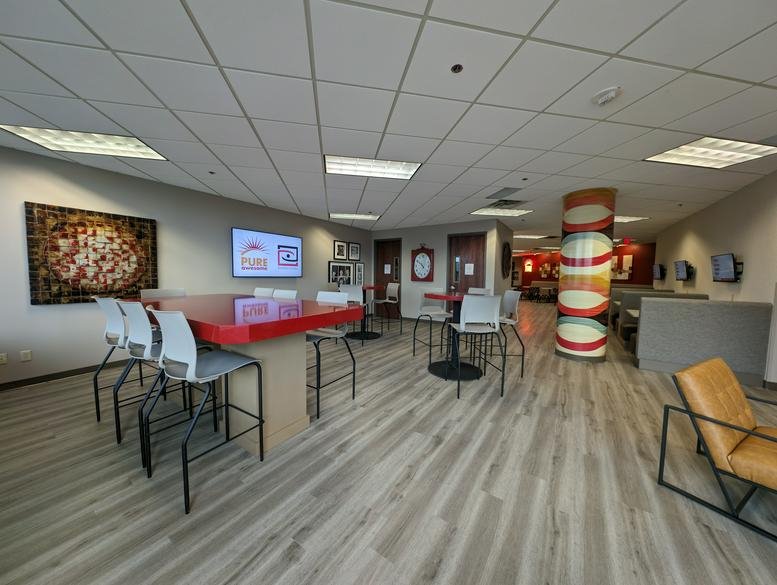 Spacious coworking area at 7900 International Drive, Suite 200 with red high-top tables and decorative pillar.