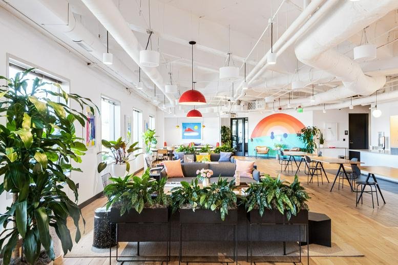 Spacious communal coworking area at 800 Bellevue Way NE featuring red pendant lights and potted plants.