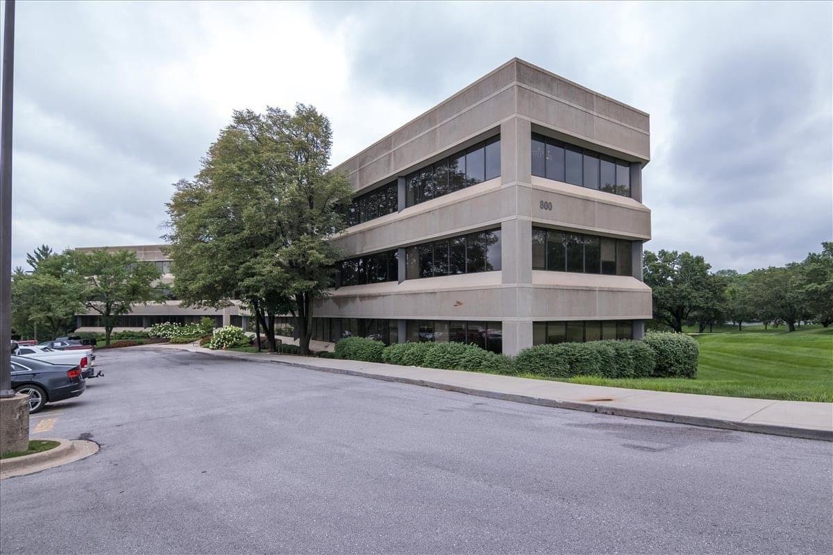 Exterior view of the multi-story Holmes Corporate Centre Building with stone facade and dark windows.