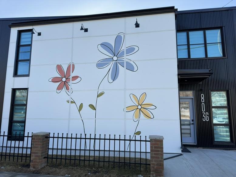 The modern exterior facade of Ramsay Junction featuring a floral mural and black corrugated siding.