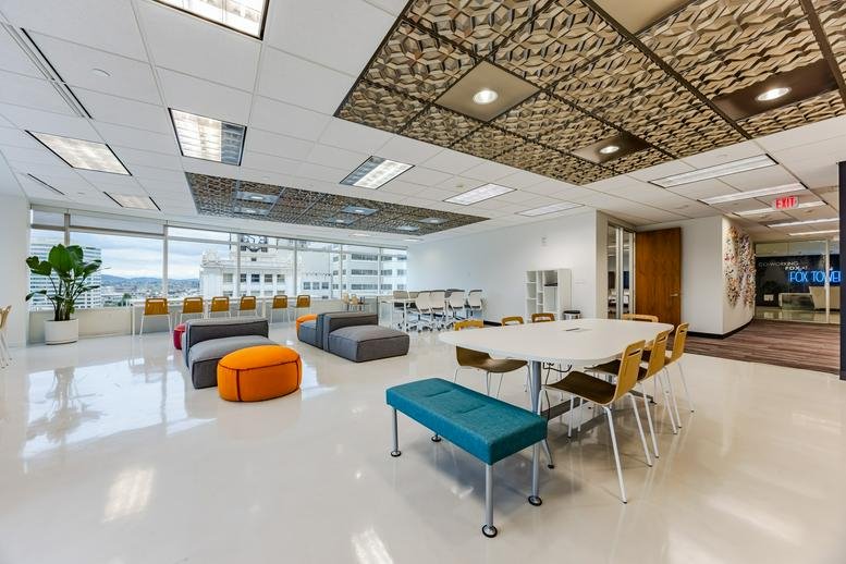 Spacious communal lounge at Co-Working PDX, Fox Tower, featuring colorful seating and patterned ceiling tiles.