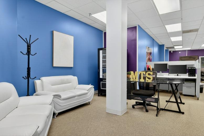 Reception area at 8101 Sandy Spring Road featuring white leather sofas and a blue feature wall.