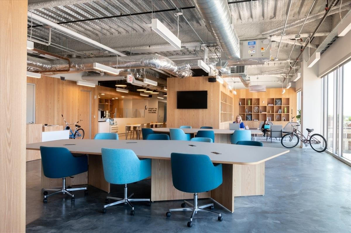 Modern coworking space at 811 East Washington Avenue featuring teal chairs and exposed ceilings.