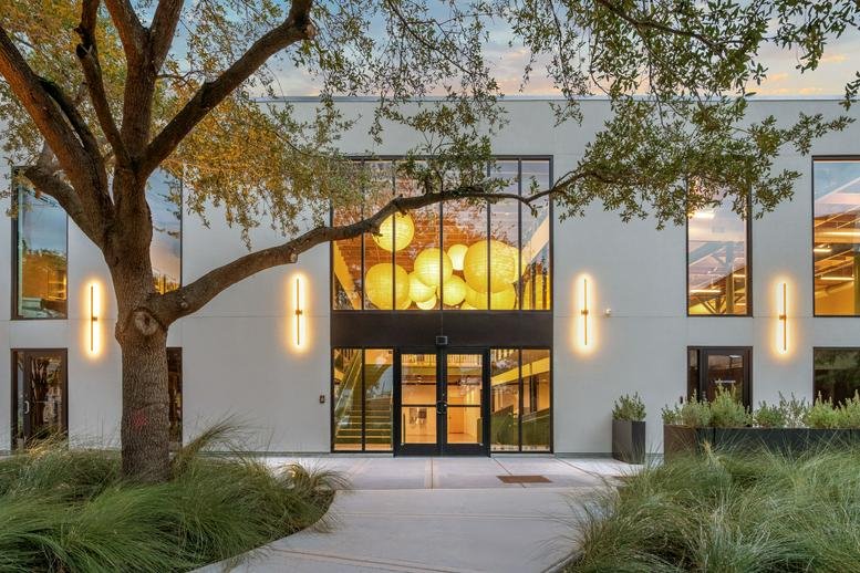 Exterior entrance of EADO Spaces on Saint Charles Street with glowing wall sconces and a large tree.