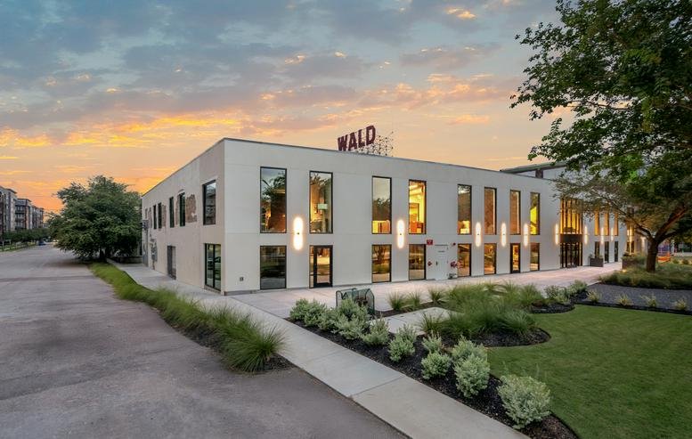 Exterior view of the EADO Spaces building at sunset with illuminated windows.