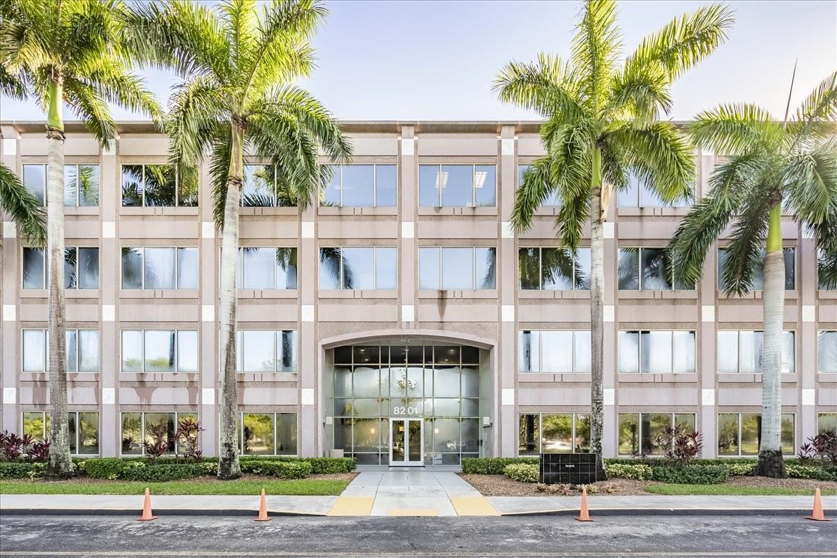 Exterior view of the multi-story Crossroads One Center at 8201 Peters Road with palm trees.