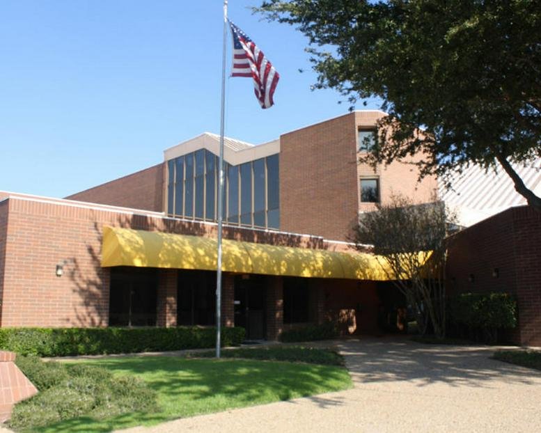Exterior brick facade and entrance of 8204 Elmbrook Dr with a yellow awning and American flag.