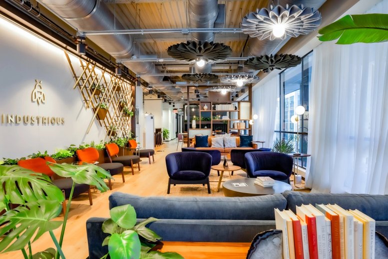 Spacious communal lounge at 823 Congress Avenue with colorful seating, plants, and branded wall.