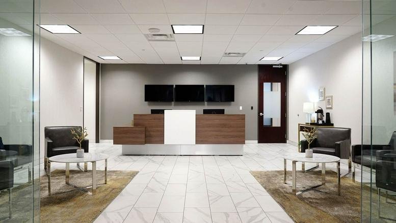 Bright lobby area with a modern wood reception desk and white tiled floor.