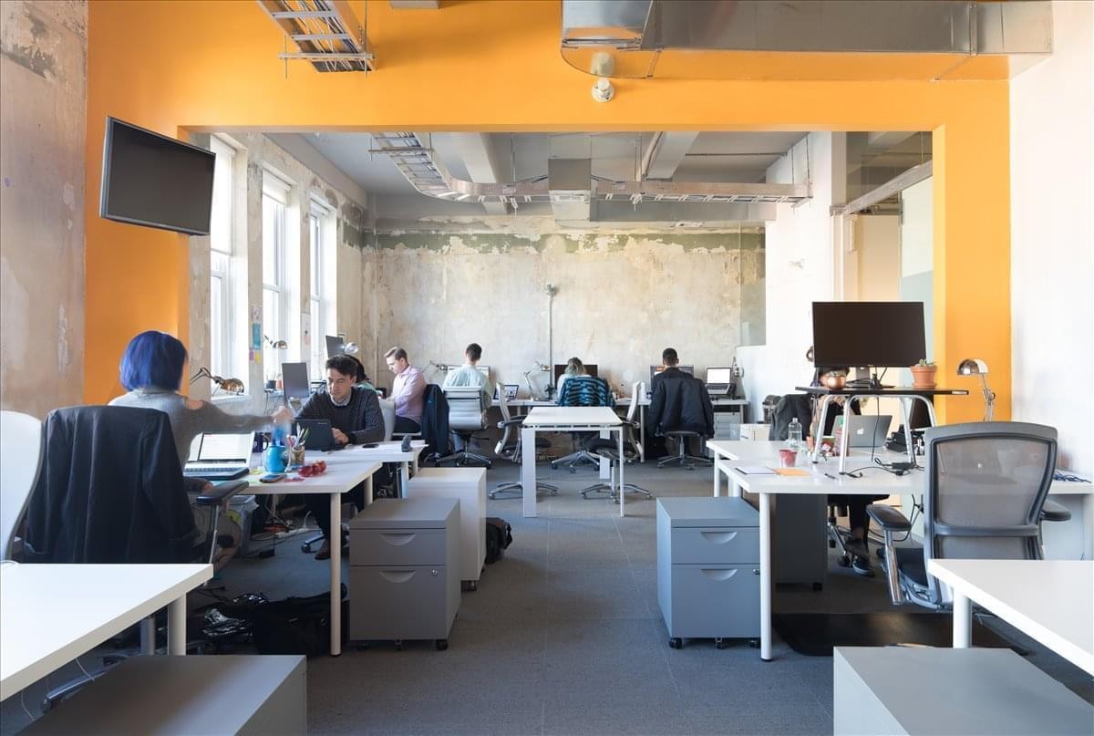 Spacious open-plan workspace at 85 Delancey Street, 2nd Floor with orange walls and natural light.