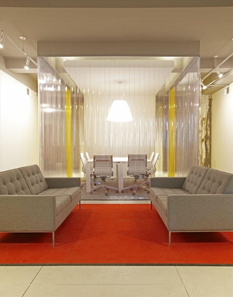 Minimalist lounge area at 85 Delancey Street, 2nd Floor featuring grey sofas and a red rug.