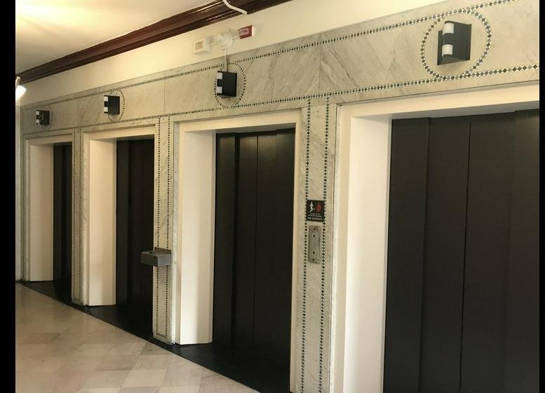 Building lobby at The City Club Building featuring several dark elevators and marble wall detailing.