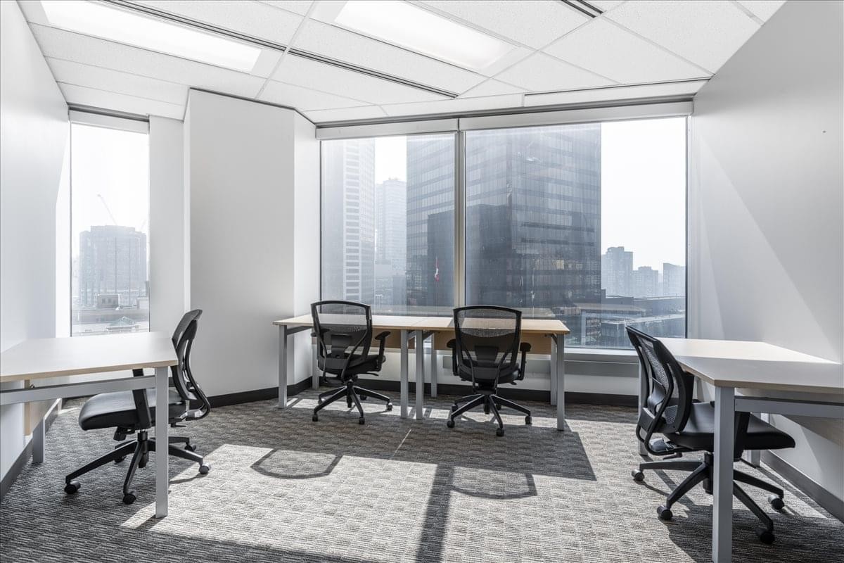 Spacious shared office with multiple desks and floor-to-ceiling city views at 885 West Georgia Street, HSBC Building.