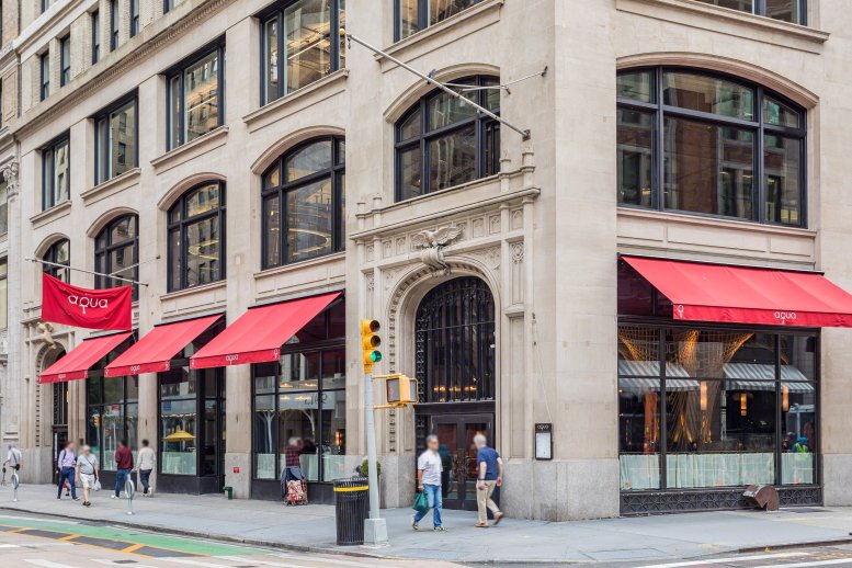 Exterior street-level view of 902 Broadway, featuring arched windows and red restaurant awnings.
