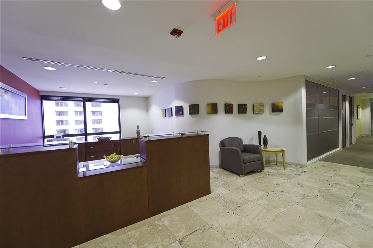 Bright reception area featuring a wood-paneled front desk and polished tile floors.