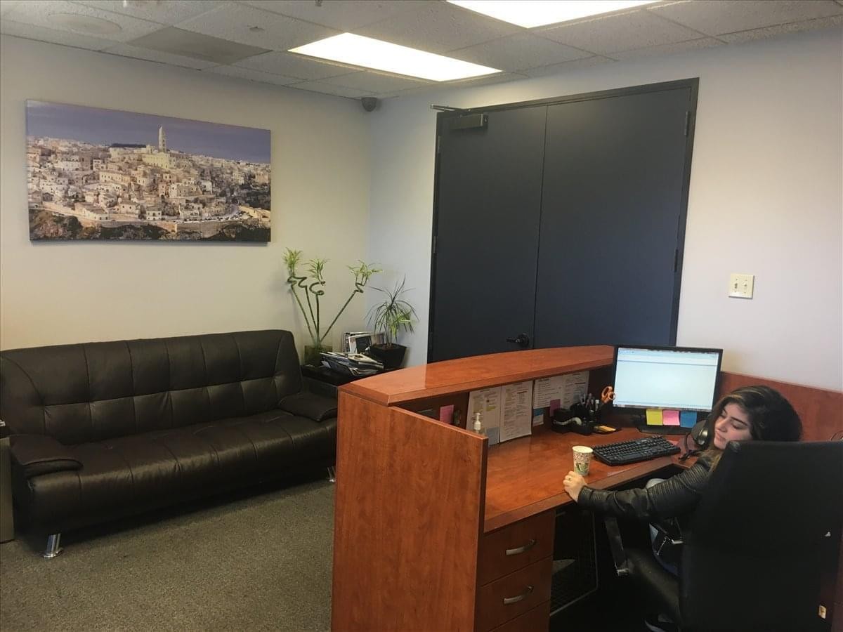 Reception area at 9107 Wilshire blvd, Suite 450, Beverly Hills featuring a wood desk and black leather sofa.