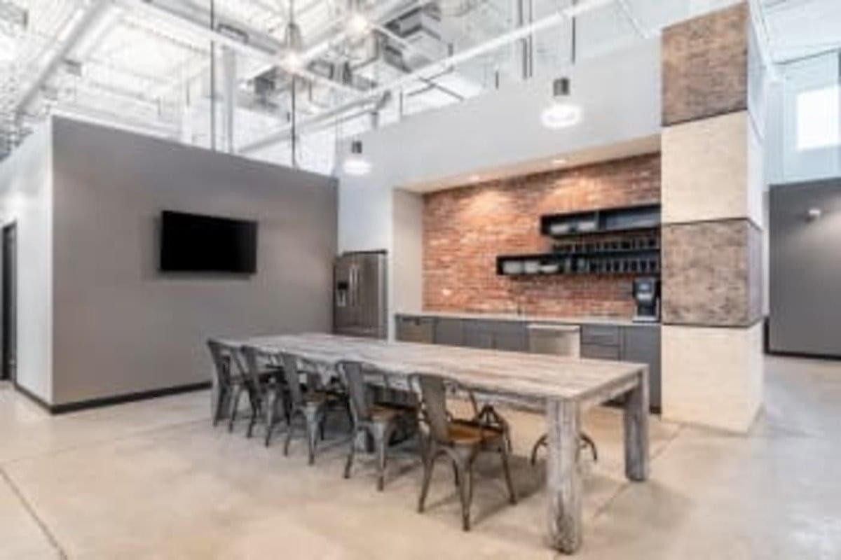 Communal break area at Keele Rutherford Corporate Centre featuring a long wooden table and brick accent wall.
