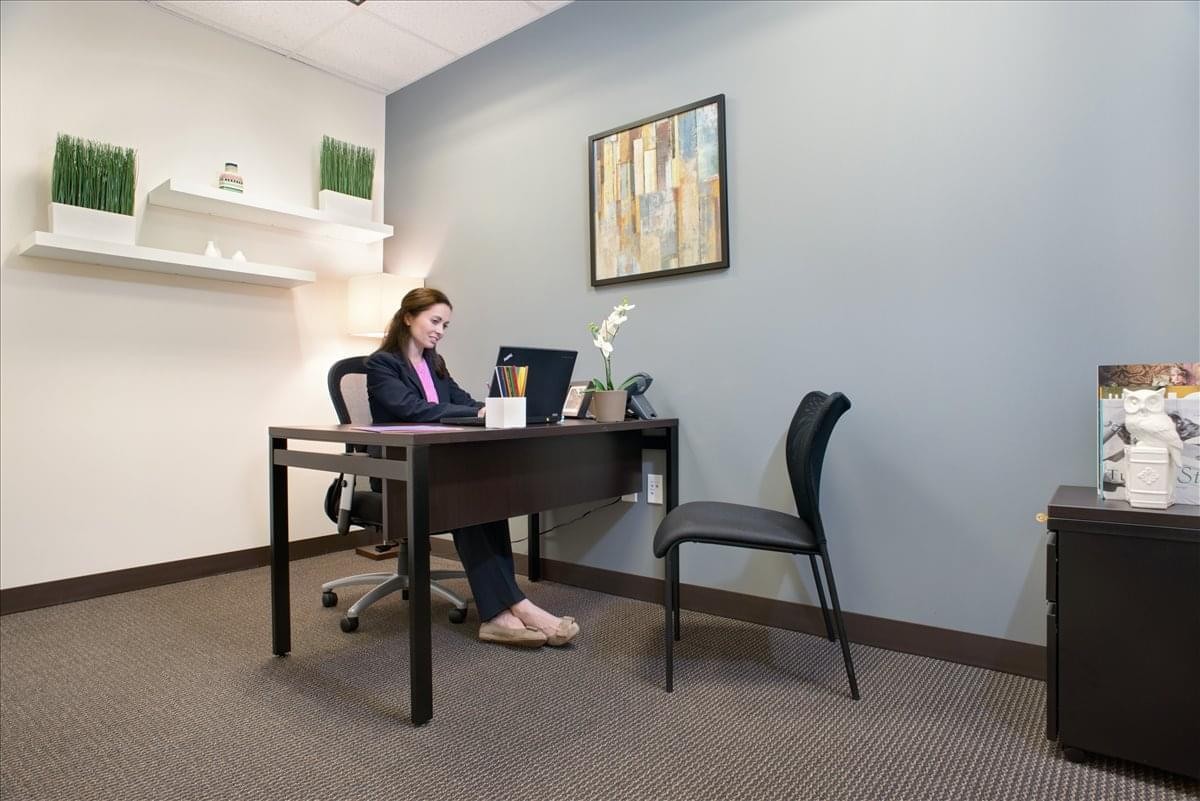 Private office at 9160 Forum Corporate Parkway, Suite 350 with a dark wood desk and wall art.