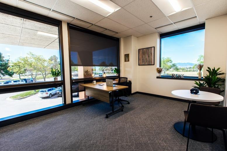 Wide view of a bright office space with multiple large windows and office furniture.