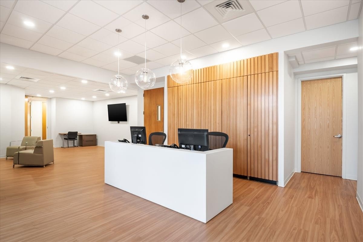Professional reception area with a sleek white front desk and wood-paneled feature wall.