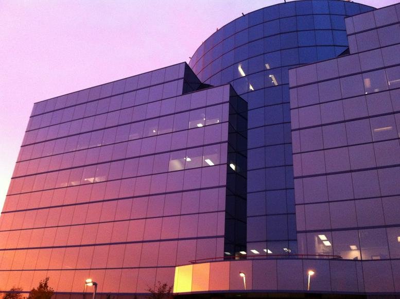 Exterior sunset view of the modern glass building at 95 Mural Street, Suite 600.